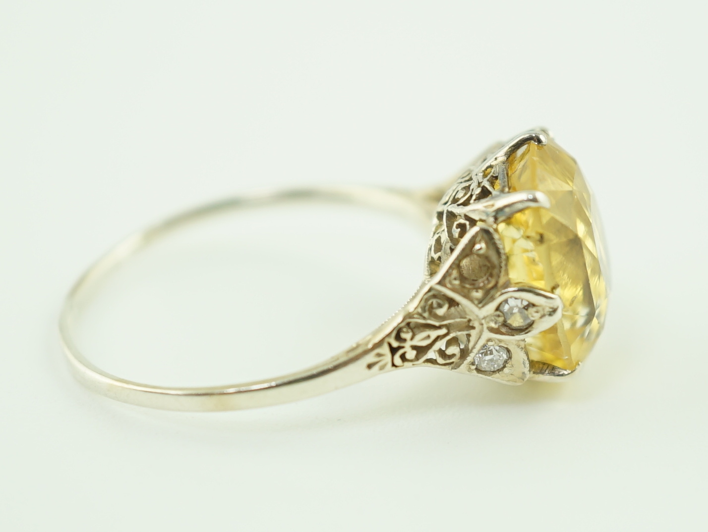 A mid 20th century platinum? and single stone fancy cushion cut yellow sapphire set dress ring with six stone diamond set pierced mount